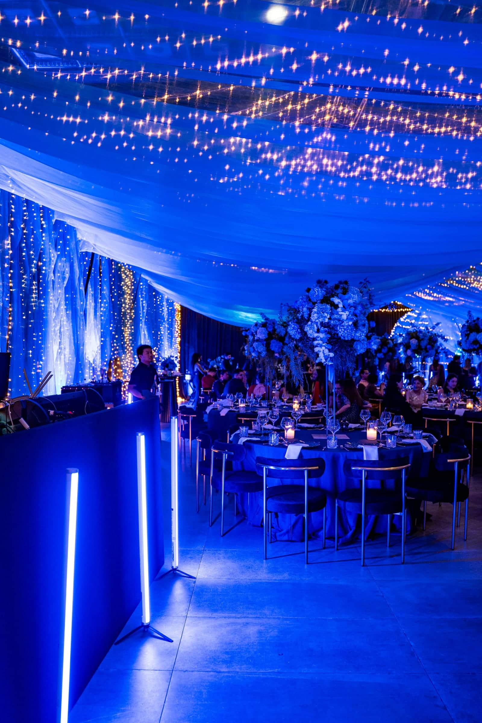 Dinner tent lit in blue with a starlight ceiling and LED light tubes
