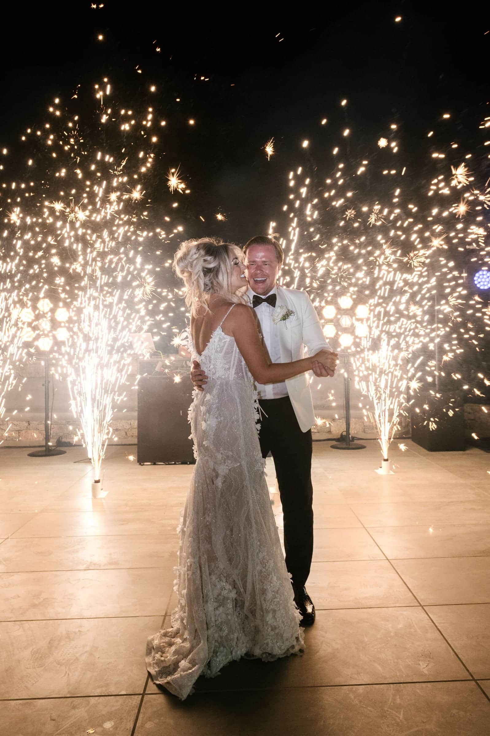 Bride and groom embracing during their first dance between cold-spark fountains
