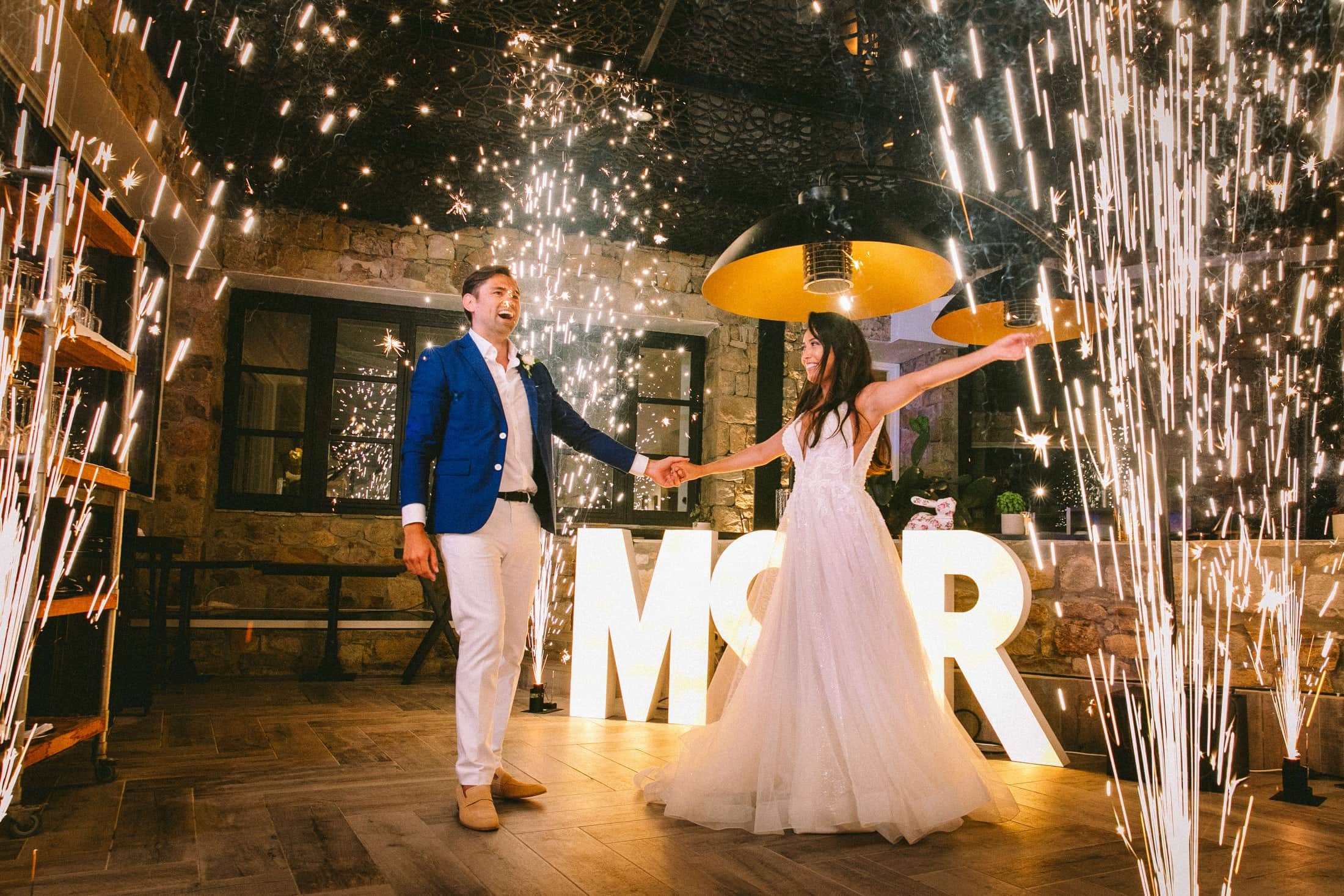 Bride and groom's first dance between cold-spark fountains and illuminated AMOR letters