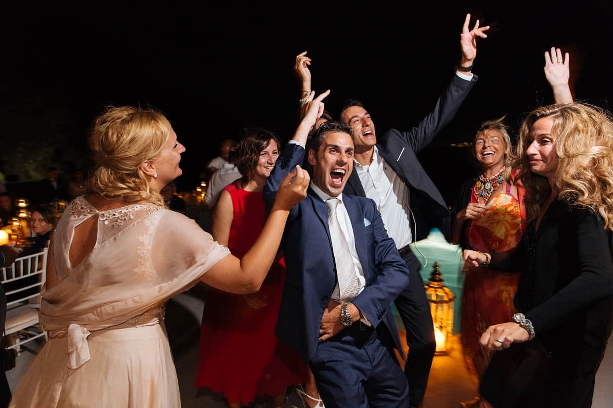 Wedding guests dancing on a candlelit poolside terrace at night
