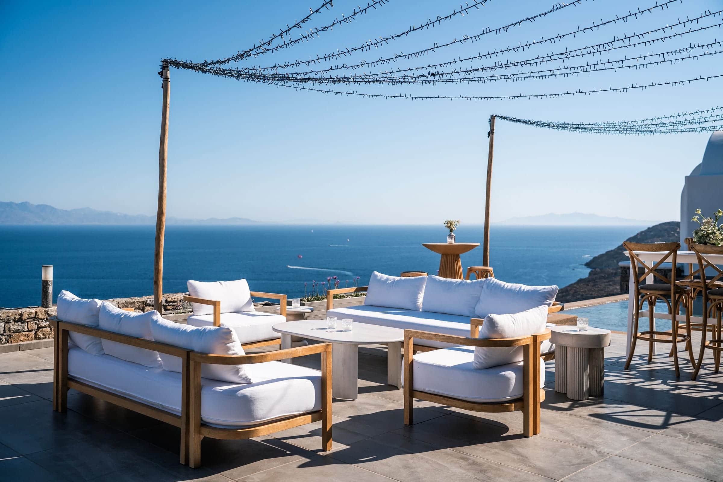 Sea-view lounge terrace under festoon string lights in daylight